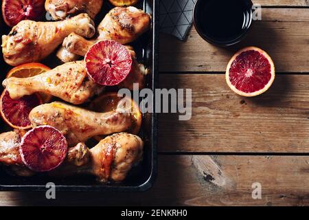Würzen Sie gebratene Hähnchendrumstick in der Bratpfanne. Gebackene Hähnchenschenkel mit Orangen. Stockfoto