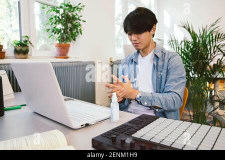 Mann, der Handdesinfektionsmittel an seinem Schreibtisch verwendet Stockfoto