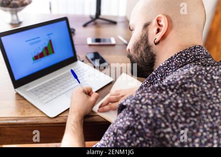 Junger Mann am Laptop zu Hause arbeiten Stockfoto