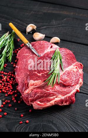 Fresh Raw Chuck Eye Roll Beef Steak auf Metzgertisch. Schwarzer Holzhintergrund. Draufsicht Stockfoto