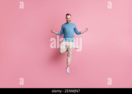 In voller Länge Foto von friedlichen charmanten jungen Kerl tragen blau pullover springen ein Bein genießen Yoga isoliert rosa Hintergrund Stockfoto