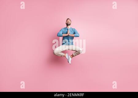 In voller Länge Foto von süßen friedlichen jungen Kerl tragen blau pullover springen genießen Yoga isoliert rosa Farbe Hintergrund Stockfoto