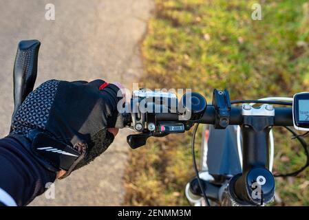 Ein Fahrradlenker aus der Perspektive der ersten Person und mit einer mans Hand am Griff. Sichtbarer Fahrradcomputer und Glocke. Stockfoto