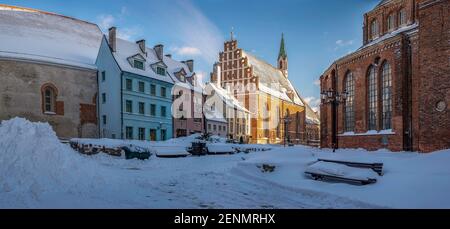 Bedeckt in Schnee Straße im historischen Stadtzentrum von Riga. Historische Häuser in der Nähe der St. Peter-Kirche im Winter in Riga, Lettland Stockfoto