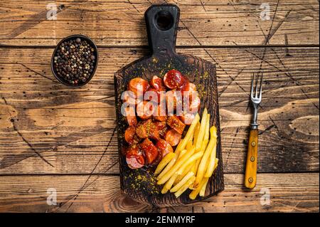 Currywurst Würstchen mit Pommes auf einem Holzbrett. Holzhintergrund. Draufsicht Stockfoto