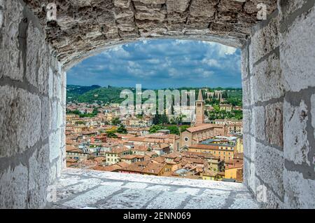 Blick von Steinfenster auf rote Dächer und Dächer in Verona, Italien. Blick von oben auf die Altstadt von Verona. Stockfoto