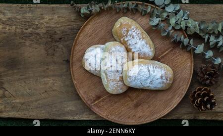 Vier hausgemachte süße Sahne weiche Brötchen und bestreut mit Puderzucker auf runden Holzteller über rustikalen Holzboden. Bäckerei und Dessert Konzept, Selecti Stockfoto