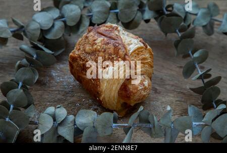 Gebackene Croissant-Wurst und getrocknete Blumen auf alten rustikalen Holzboden. Bäckerei- und Dessertkonzept, selektiver Fokus. Stockfoto