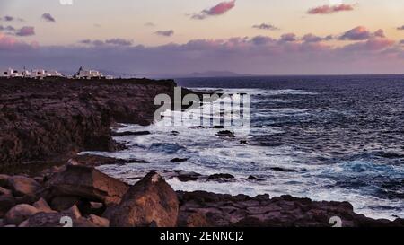 Häuser auf einem Felsen an der Küste von Playa Blanca In Lanzarote bei Sonnenuntergang Stockfoto