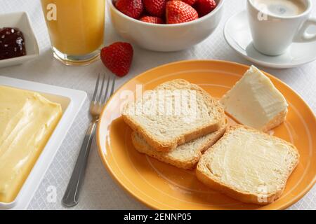 Frühstückstisch mit Butter, Toast, Marmelade und Erdbeeren. Stockfoto