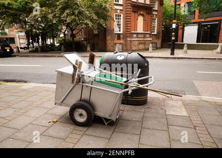 Straßensauerset mit Bürsten und Schaufel auf Rädern und Mülltonne in London. Stockfoto