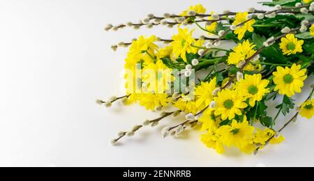 Gelbe Chrysanthemen und Weidenzweige Bouquet auf dem weißen Tisch horizontal. Schöne Grußkarte für Muttertag oder Osterferien. Draufsicht, Stockfoto