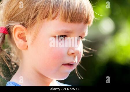 Junges Kind, kleines Mädchen einfaches Porträt, Gesichtsausdruck Detail extreme Nahaufnahme, im Freien Szene, verschwommener Hintergrund. Schulalter kaukasischen Kind tief Stockfoto