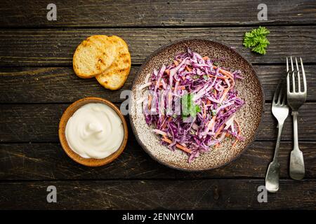 Frischer Krautsalat aus geriebenem Rot- und Weißkohl und Karotten mit Mayonnaise-Sauce auf dunklem Holzhintergrund, Draufsicht Stockfoto