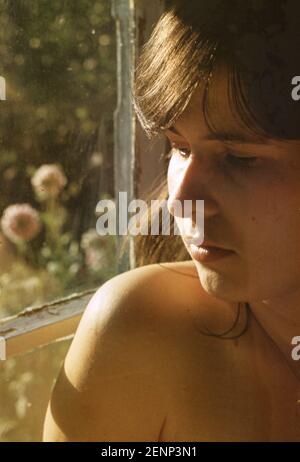 Porträt einer jungen Frau an einem Fenster in einem Haus Stockfoto