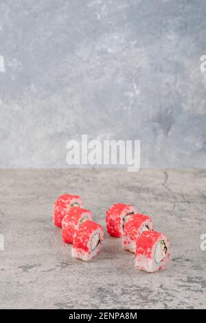 Köstliche Sushi-Brötchen mit rotem Kaviar auf Marmortisch Stockfoto