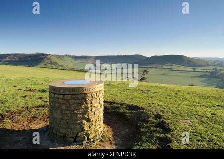 Trig Point auf Cadbury Castle mit weitreichenden Aussichten auf Somerset, Großbritannien. Stockfoto