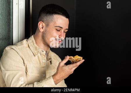 kaukasischer Kerl mit Schnurrbart isst ein Stück Pizza Stockfoto