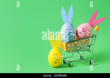 Warenkorb voller Ostereier, auf grünem Hintergrund, Kopierraum. Verkaufskonzept Stockfoto