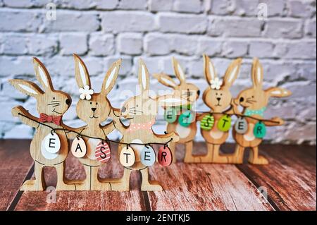 Hölzerne Osterhasen mit Dekoration und dem Text Ostern auf Eiern geschrieben. Stockfoto