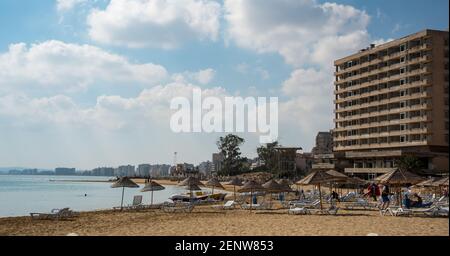 Palm Beach mit Sonnenschirmen und Touristen und verlassenen Hotels in Geisterstadt, Famagusta, Nordzypern Stockfoto