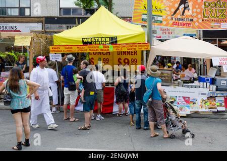 Salsa auf St. Saint Clair Festival Szenen: Kunden stehen an Outdoor-Food-Stand Verkauf mexikanisches Essen. Einige der Leute nehmen sich Zeit, um die zu lesen Stockfoto