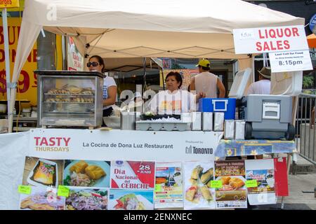 Salsa auf St. Saint Clair Festival Szenen: Ein Imbalstand auf einem Straßenfest wird von einer großen weißen Markise mit einem Schild beschattet, das den Verkauf von Spirituosen wirbt Stockfoto