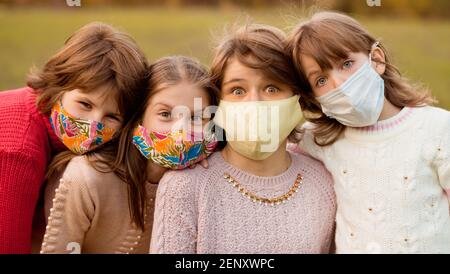 Eine Gruppe von vier Freundinnen im Schulalter, die Schutzmasken tragen, warten auf das Ende der pandemischen Sperre, auf Freiheit und zurück zum normalen Lebensstil Stockfoto