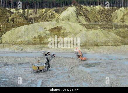 Bagger im Steinbruch lädt Gestein in einen Bergbauwagen. Bagger und Lastwagen arbeiten in einer Kreidegrube. Luftaufnahme der Bergschlucht mit Bergen und Stockfoto