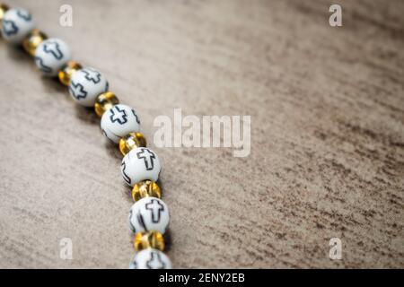 Niedliches weißes und goldenes religiöses Armband mit Kreuzen auf einem Holztisch Stockfoto