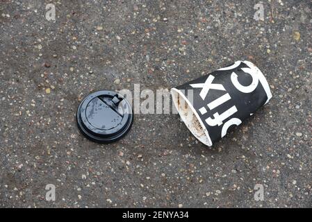 14 Feb 2020, Minsk, Weißrussland: Schwarze Papierkaffeetasse liegt auf dem Bürgersteig in der Stadt. Die Leute werfen вisposable Kaffeetassen auf die Straße. Das Problem o Stockfoto