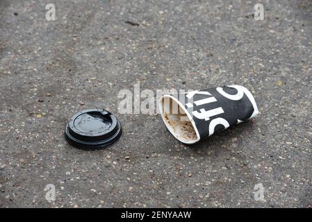 14 Feb 2020, Minsk, Weißrussland: Schwarze Papierkaffeetasse liegt auf dem Bürgersteig in der Stadt. Die Leute werfen вisposable Kaffeetassen auf die Straße. Das Problem o Stockfoto