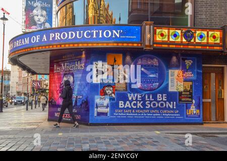 Eine Frau geht an einem Schild "We'll Be Back Soon" im Sondheim Theatre auf der Shaftesbury Avenue vorbei, das seit Beginn der Coronavirus-Pandemie seit langem geschlossen ist. London, Großbritannien Februar 2021. Stockfoto