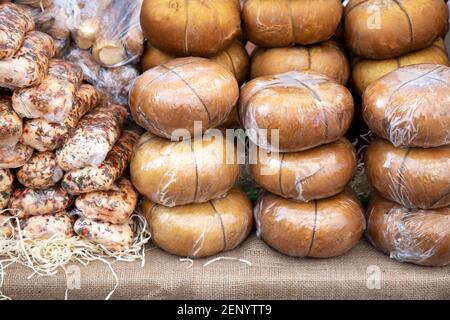 Verschiedene geräucherte Adyghe Käse in Packungen und in der Masse auf Marktzähler Stockfoto