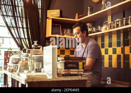 Barista im farbenfrohen Café, das hinter dem Tresen serviert wird Stockfoto