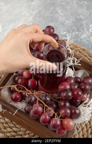 Weibliche Hand nimmt Glas Saft aus Holzkiste Stockfoto