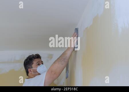 Auftragnehmer mit Sandkelle Schleifen der Trockenwand an der Wand Stockfoto