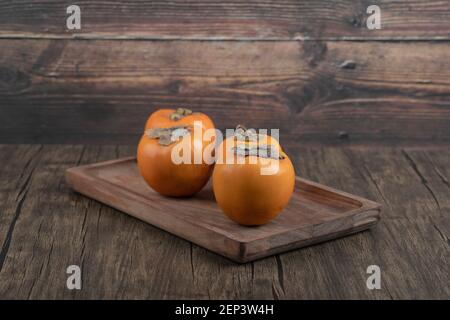Teller mit leckeren fuyu-Kaki-Früchten auf Holzoberfläche Stockfoto