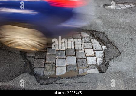 Leipzig, Deutschland. Februar 2021, 19th. Ein Auto fährt über eine Straße mit Schlaglöchern. Wie in jedem Winter sind die Straßen besonders durch den Wechsel von Frost und Tauwetter betroffen. Quelle: Jan Woitas/dpa-Zentralbild/dpa/Alamy Live News Stockfoto