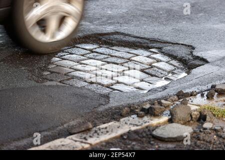 Leipzig, Deutschland. Februar 2021, 19th. Ein Auto fährt über eine Straße mit Schlaglöchern. Wie in jedem Winter sind die Straßen besonders durch den Wechsel von Frost und Tauwetter betroffen. Quelle: Jan Woitas/dpa-Zentralbild/dpa/Alamy Live News Stockfoto