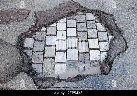 Leipzig, Deutschland. Februar 2021, 19th. Das Wasser sammelt sich während des Tauens in einem frischen Schlagloch. Wie in jedem Winter sind die Straßen besonders durch den Wechsel von Frost und Tauwetter betroffen. Quelle: Jan Woitas/dpa-Zentralbild/dpa/Alamy Live News Stockfoto