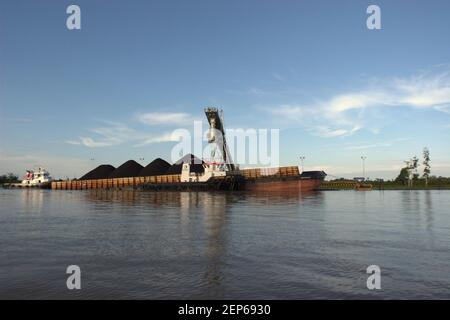 Ein Lastkahn wird an einer Tankstelle am Ufer des Mahakam-Flusses in der Provinz Ost-Kalimantan, Indonesien, mit Kohle beladen. Stockfoto