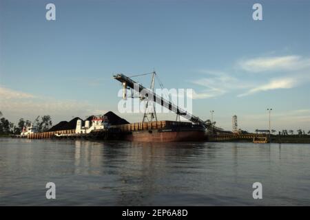 Ein Lastkahn wird an einer Tankstelle am Ufer des Mahakam-Flusses in der Provinz Ost-Kalimantan, Indonesien, mit Kohle beladen. Stockfoto