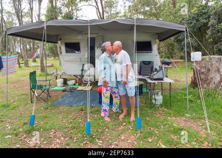 Graue Nomaden, Vicki und Gary (Middo) Middleton vor ihrem Wohnwagen und Markise auf einem Campingplatz in Bendelong, New South Wales, Australien Stockfoto