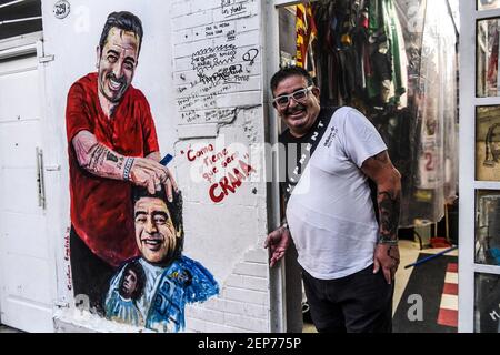 Buenos Aires, Argentinien. Februar 2021, 12th. Julio Pan steht neben einem Wandgemälde am Eingang seines Friseursalons, wo er zahlreiche Souvenirs zu Ehren des Fußballstars Maradona aufbewahrt und ausgestellt hat. (To dpa 'Maradonas Vermächtnis: Zwischen heiliger Anbetung und Schlammschlachten' von 27,02.2021) Credit: Fernando Gens/dpa/Alamy Live News Stockfoto