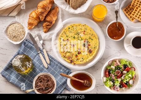 Große Auswahl an Speisen, darunter Omelette, Croissants, Salat, Brot, Haferflocken, Marmelade, Waffeln, Honig, Choclate-Aufstrich, Kaffee und Orangensaft serviert Stockfoto