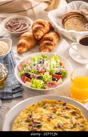 Große Auswahl an Speisen, darunter Omelette, Croissants, Salat, Brot, Haferflocken, Marmelade, Waffeln, Honig, Choclate-Aufstrich, Kaffee und Orangensaft serviert Stockfoto