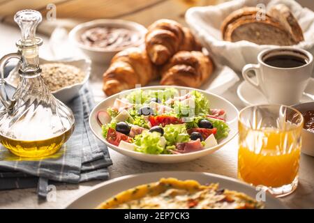 Große Auswahl an Speisen, darunter Omelette, Croissants, Salat, Brot, Haferflocken, Marmelade, Waffeln, Honig, Choclate-Aufstrich, Kaffee und Orangensaft serviert Stockfoto