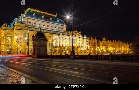 Tschechische Republik, Prag, 16. April 2016, Theatergebäude mit Abendbeleuchtung. Lange Lichterketten von Autos, die sich entlang der Straße bewegen. Stockfoto