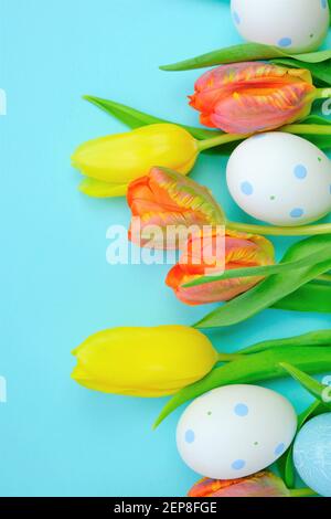 Osterfeiertag.Orange und gelbe Tulpen und dekorative Eier auf einem hellen blauen Hintergrund.Copy space.Frühling religiösen Feiertag Symbol. Ostern festlich Stockfoto